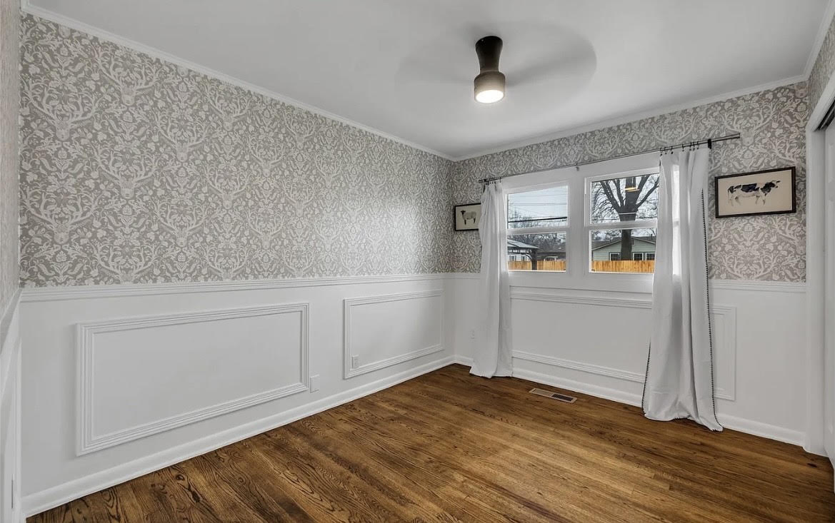 Finished room showing coordinated wallpaper, wall trim, wood flooring, and lighting